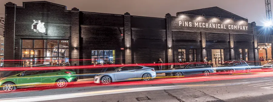 Exterior photo of Pins Mechanical Co. Nashville with two cars parked to the left in the photo