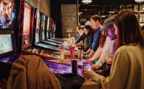 People play pinball on arcade machines.